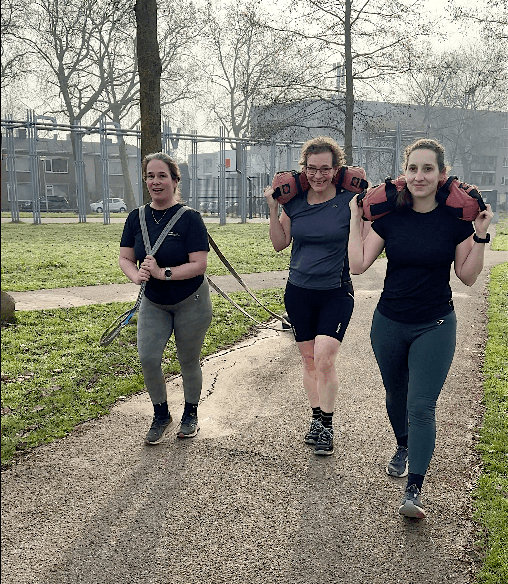 Sjouwen Deelnemers aan Heavy Duty Bootcamp in Nijmegen trainen buiten met extra weerstand